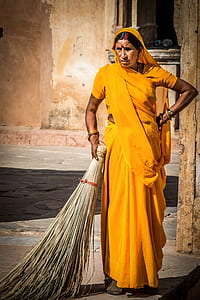 woman in yellow sari dress holding broomstick thumbnail