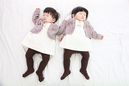 two babies lying on white surface thumbnail