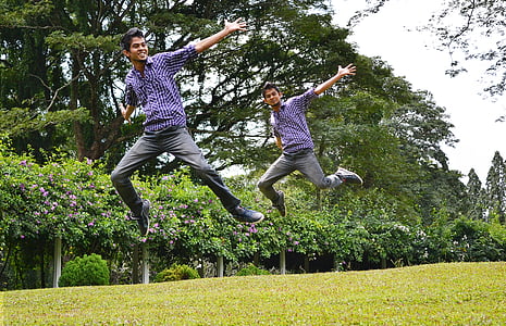 two men in blue shirt jumping on grass field during day thumbnail