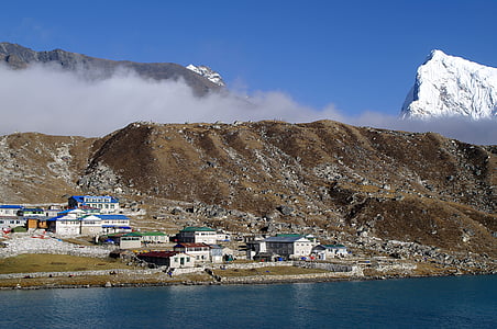 white house beside mountain near body of water at daytime thumbnail