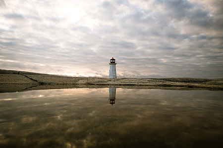 white lighthouse under cloudy sky thumbnail