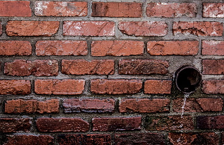 Round Brown Pipe Drainage With Liquid in Brown Bricked Concrete Wall thumbnail