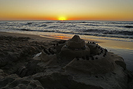 sand castle near body of water during golden hour thumbnail