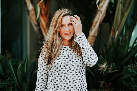 woman in white and gray long-sleeved top in front of green plants photo thumbnail