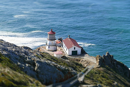white and brown house beside lighthouse in front of ocean thumbnail