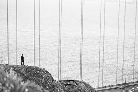 Man Stands at The Edge of The Cliff Near The Golden Gate Bridge thumbnail