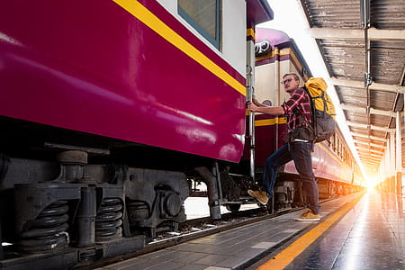 Man With Yellow and Black Backpack Standing Near Train thumbnail