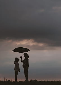 silhouette photo of woman holding umbrella standing in front of girl thumbnail