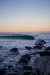 sea waves on assorted rocks under white clouds and blue sky thumbnail