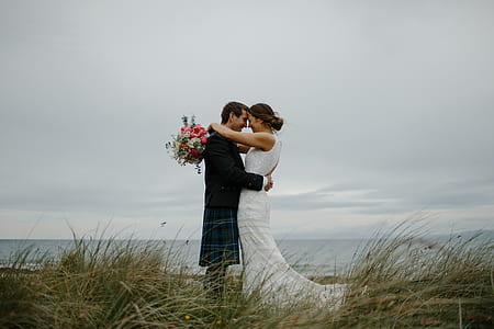 groom and bride on top of grassy hill hugging thumbnail