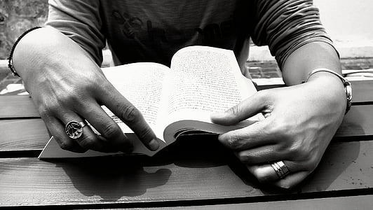 closeup photo of person reading book on table thumbnail