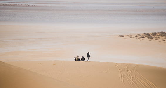 three person sitting and standing in middle of desert thumbnail