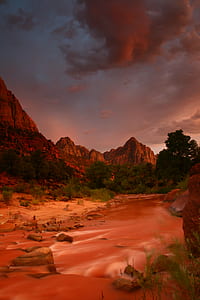 photography of brown cliff covered with trees and river thumbnail