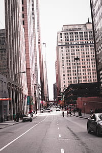 Photo of People Crossing Through Street in the Middle of Buildings thumbnail
