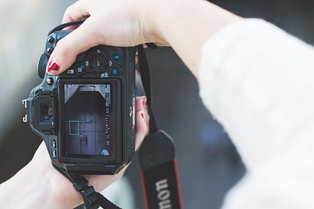person holding Canon DSLR camera taking photo of three men on the street thumbnail