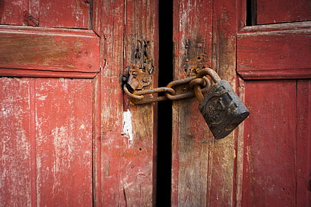 closeup photo of rusted black and brown padlock with rusted brown keychain locked on brown wooden door panel thumbnail