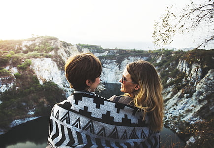 two women wrapped in gray and black blanket in mountain thumbnail