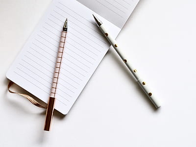 two ballpoints pen on top of black-line paper thumbnail