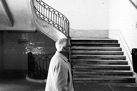 Grayscale Photography of Man Walking Near Staircase thumbnail