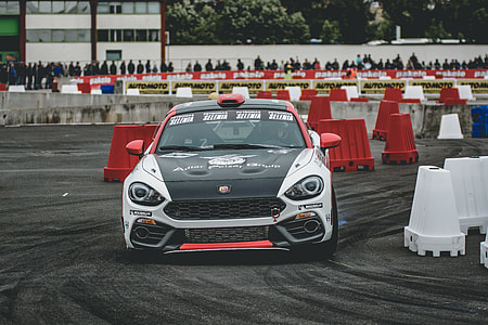 white, black, and red racecar driving on circuit track during daytime thumbnail