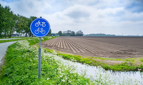 blue and white road signage near cultivated field thumbnail