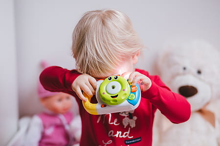 close-up photo of boy covering both eyes while holding plastic toy thumbnail