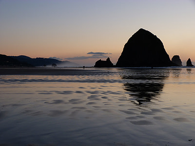 silhouette of rock near sea at golden hour thumbnail