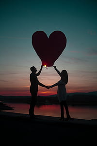 couple holding paper lantern near beach thumbnail