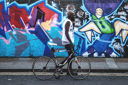A man with a bicycle walks past vibrant street art in Shoreditch in East London. Image captured with a Canon 6D thumbnail