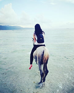 woman riding on horse with black backpack thumbnail