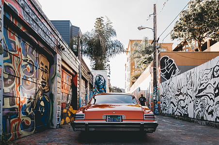 vintage orange car between walls with graffiti thumbnail