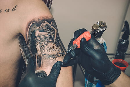 person holding orange tattoo machine thumbnail