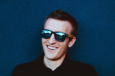 man leaning on black wall while smiling thumbnail