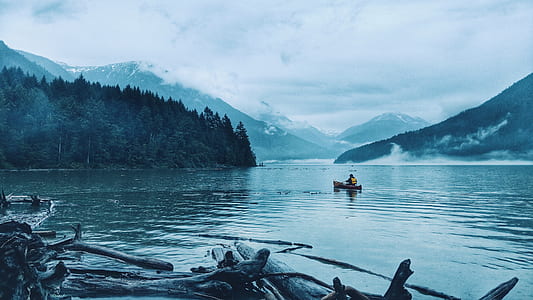 person riding boat on body of water near mountain thumbnail