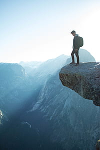 person standing on the top edge of mountain cliff thumbnail