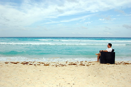 man in white shirt sitting on armchair near body of water thumbnail