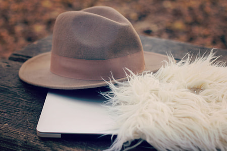 grey fedora hat on silver laptop beside a white fur textile thumbnail