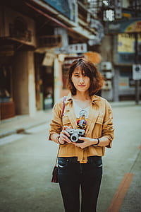 woman holding DSLR camera standing on street thumbnail