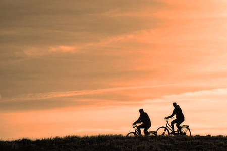 two silhouette of man riding bicycle during golden hour time thumbnail