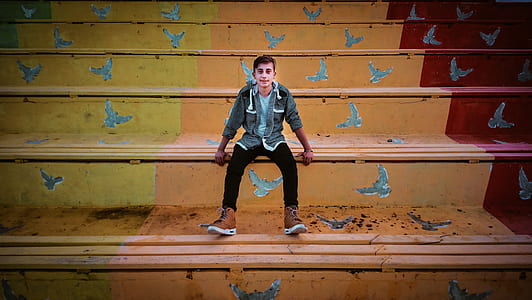 Man in Grey Zip-Up Hoodie And Black Fitted Jeans Sitting thumbnail