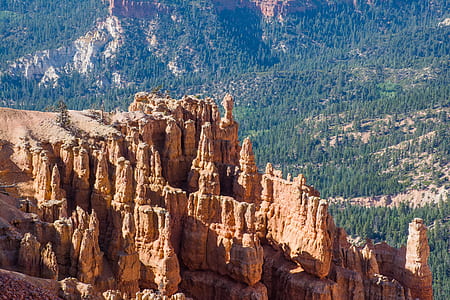 brown rock formations with view of tree-covered mountain aerial photo thumbnail