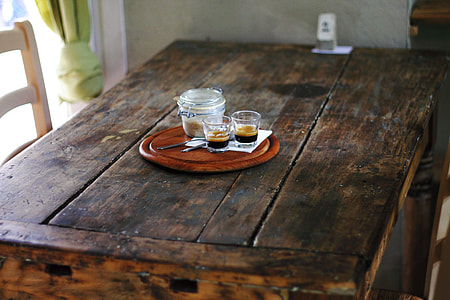 two shot glasses beside mason jar on round brown wooden tray thumbnail