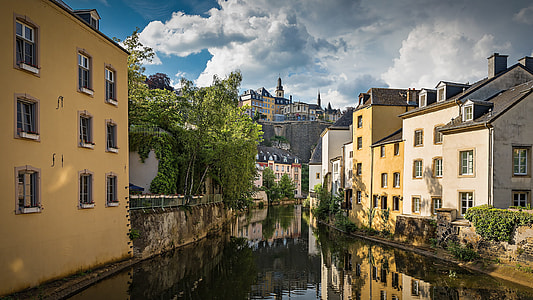 buildings beside river under white and blue skies thumbnail