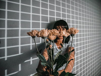 woman holding beige petaled flowers thumbnail