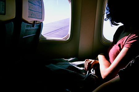 woman wearing red t-shirt inside airplane beside window thumbnail