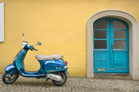 blue motor scooter beside yellow concrete house thumbnail