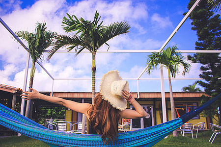 woman in white summer hat sitting on blue hammock during daytime thumbnail