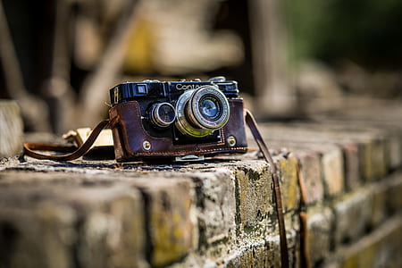 black and brown point-and-shoot camera on brown concrete fence thumbnail