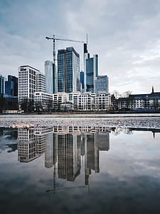 photo of gray high rise buildings reflect on water during daytime thumbnail