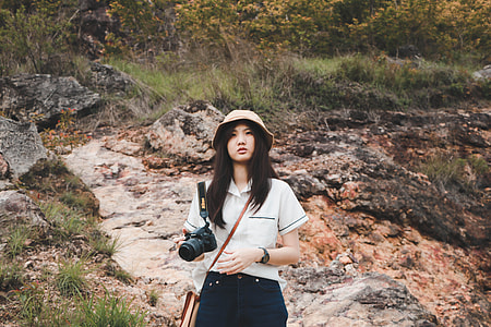 woman wearing white top holding camera thumbnail